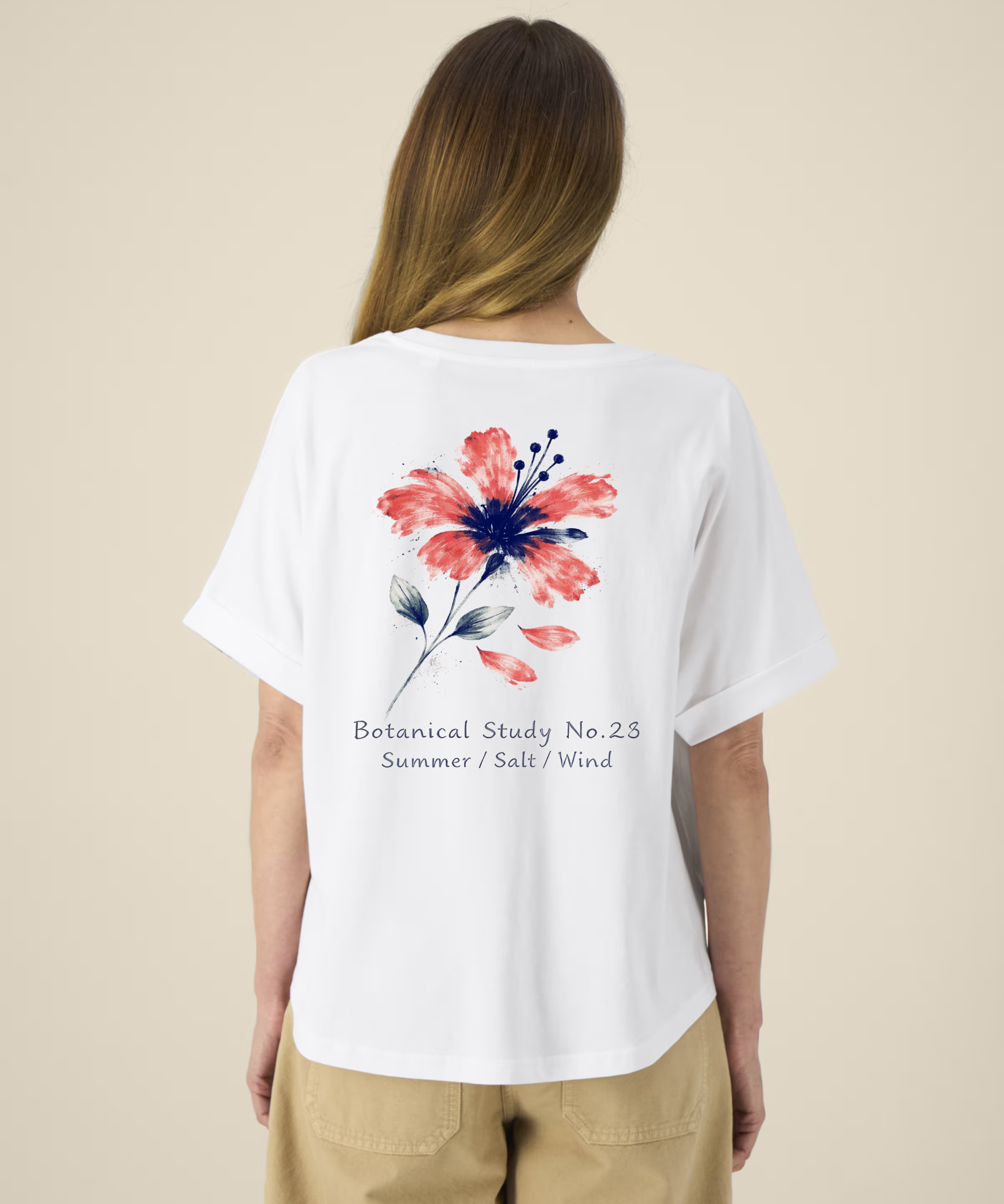 Femme de dos portant un t-shirt blanc à manches courtes avec une illustration de fleur d'hibiscus rouge et bleue et l'inscription "Botanical Study No.23".