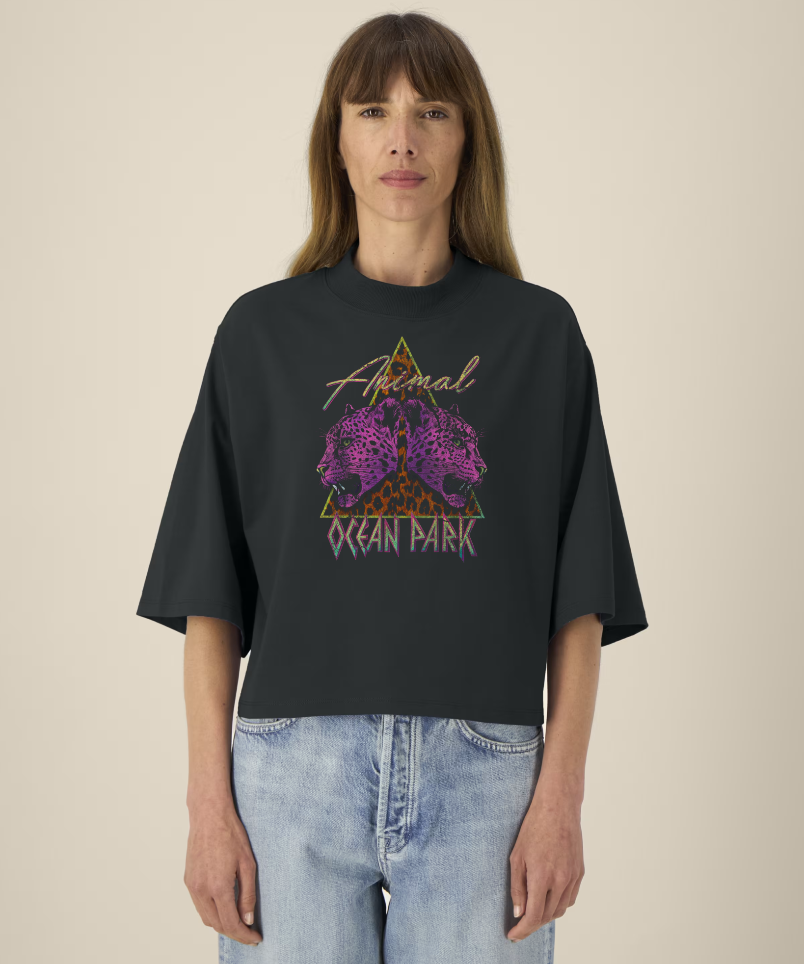 Femme portant un t-shirt noir court à col montant et manches larges avec un graphisme de triangle léopard et deux têtes de léopards violets, incluant les textes "Animal" et "Ocean Park".