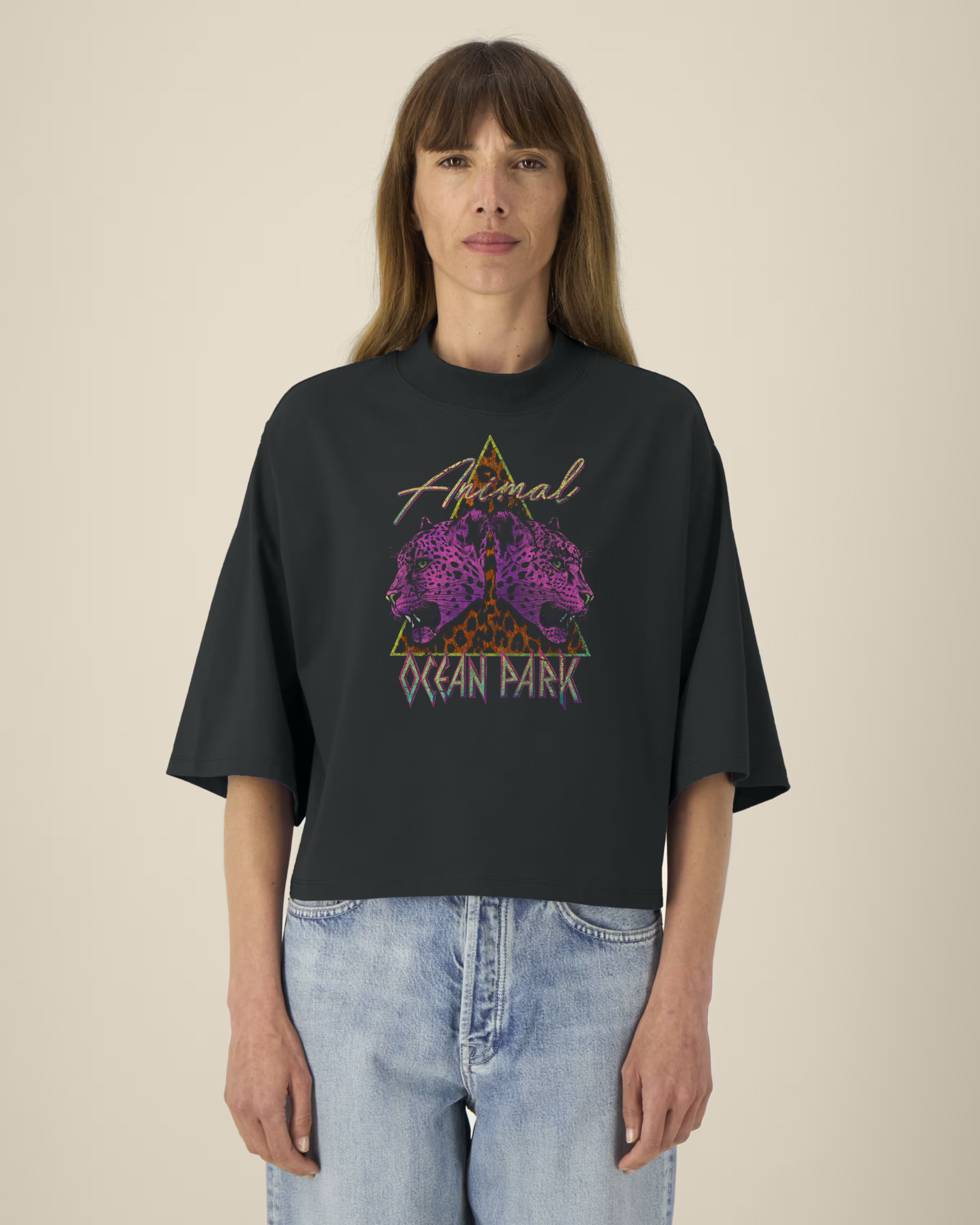 Femme portant un t-shirt noir court à col montant et manches larges avec un graphisme de triangle léopard et deux têtes de léopards violets, incluant les textes "Animal" et "Ocean Park".