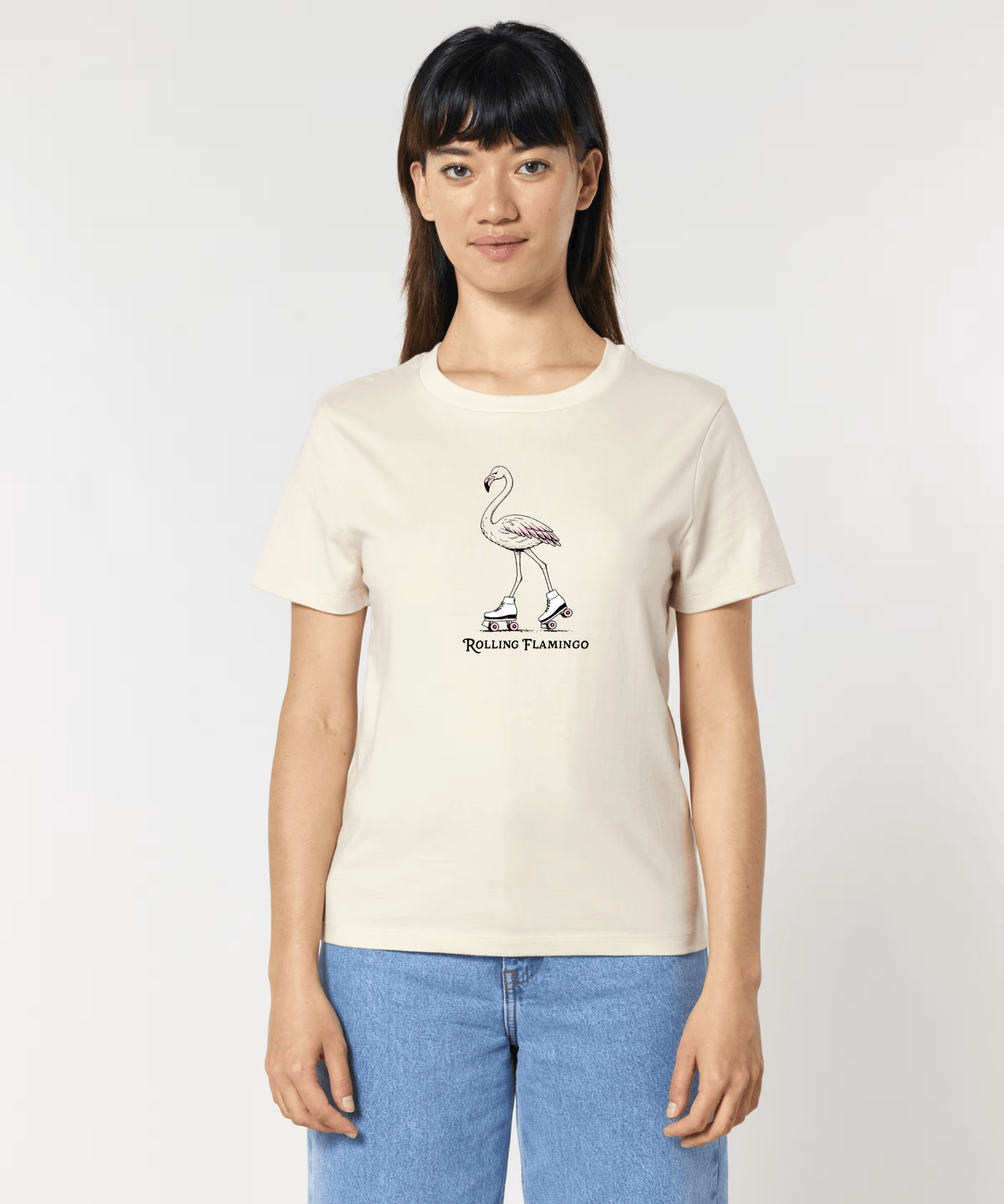 Femme de face portant un t-shirt blanc cassé avec une illustration centrale d'un flamant rose chaussé de patins à roulettes rétro, surmontant l'inscription "Rolling Flamingo".