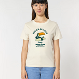 Femme de face portant un t-shirt de couleur blanc cassé naturel avec une illustration centrale d'un toucan tenant une planche de surf, entouré des textes "RELAX ALL DAY" et "wave free call the Ocean".