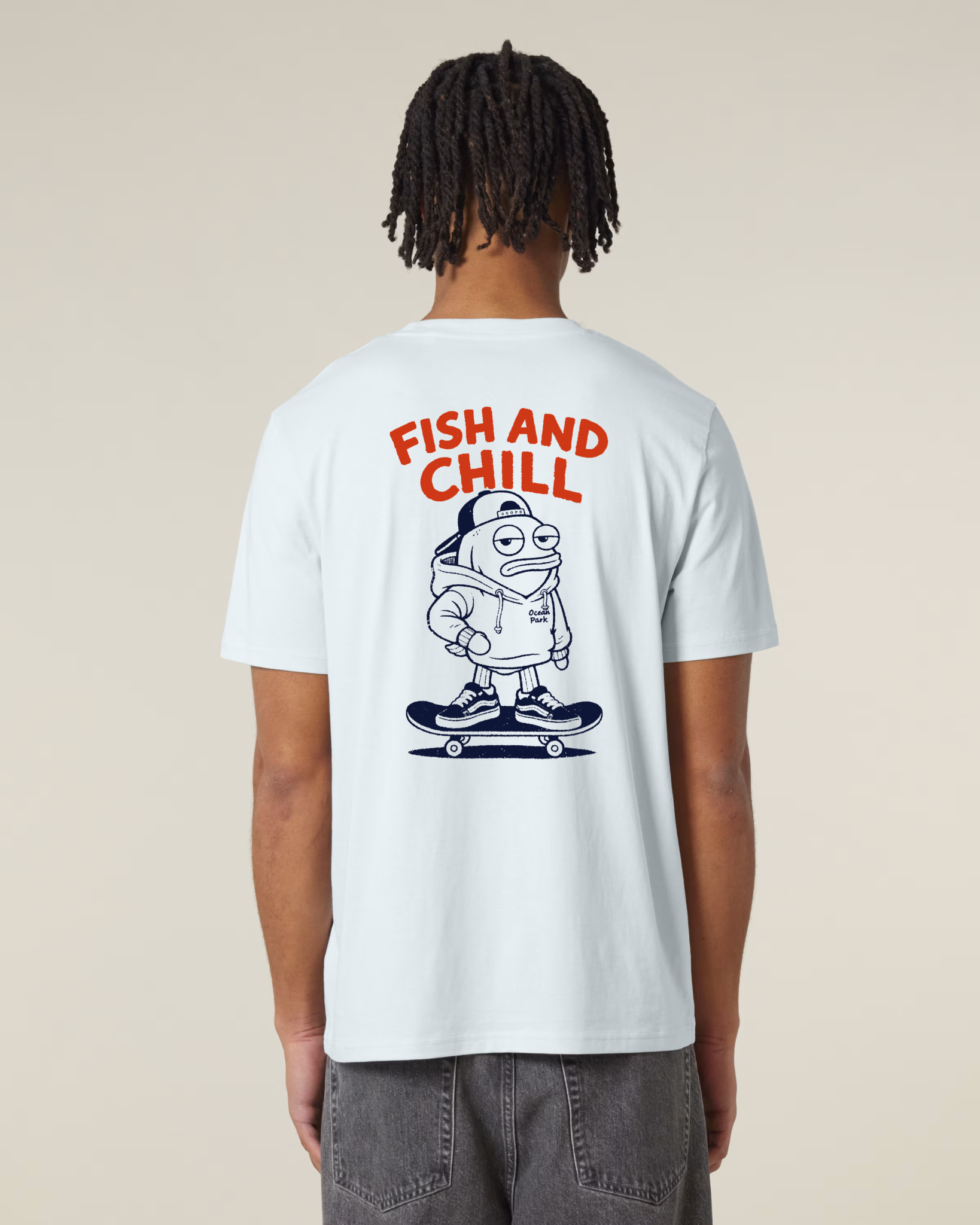 Vue de dos d'un homme portant un t-shirt bleu très clair (Blue Ice) avec une grande illustration centrale d'un poisson portant un sweat et une casquette, debout sur un skateboard, surmontée du texte rouge "FISH AND CHILL".