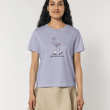 Femme de face portant un t-shirt lilas avec une illustration centrale d'un flamant rose portant des patins à roulettes blancs, accompagnée de l'inscription "Rolling Flamingo".