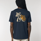 Vue de dos d'un homme portant un t-shirt bleu marine avec une grande illustration centrale composée d'un palmier beige, d'une vague stylisée et d'un soleil orange vif.