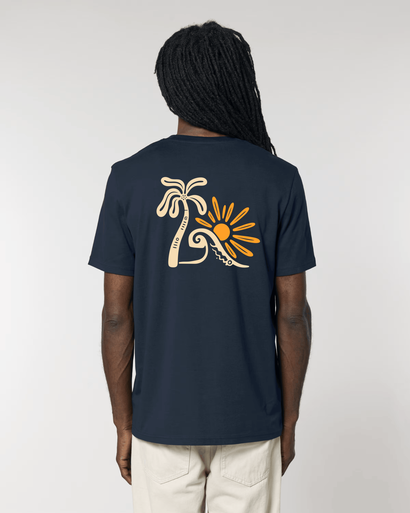 Vue de dos d'un homme portant un t-shirt bleu marine avec une grande illustration centrale composée d'un palmier beige, d'une vague stylisée et d'un soleil orange vif.