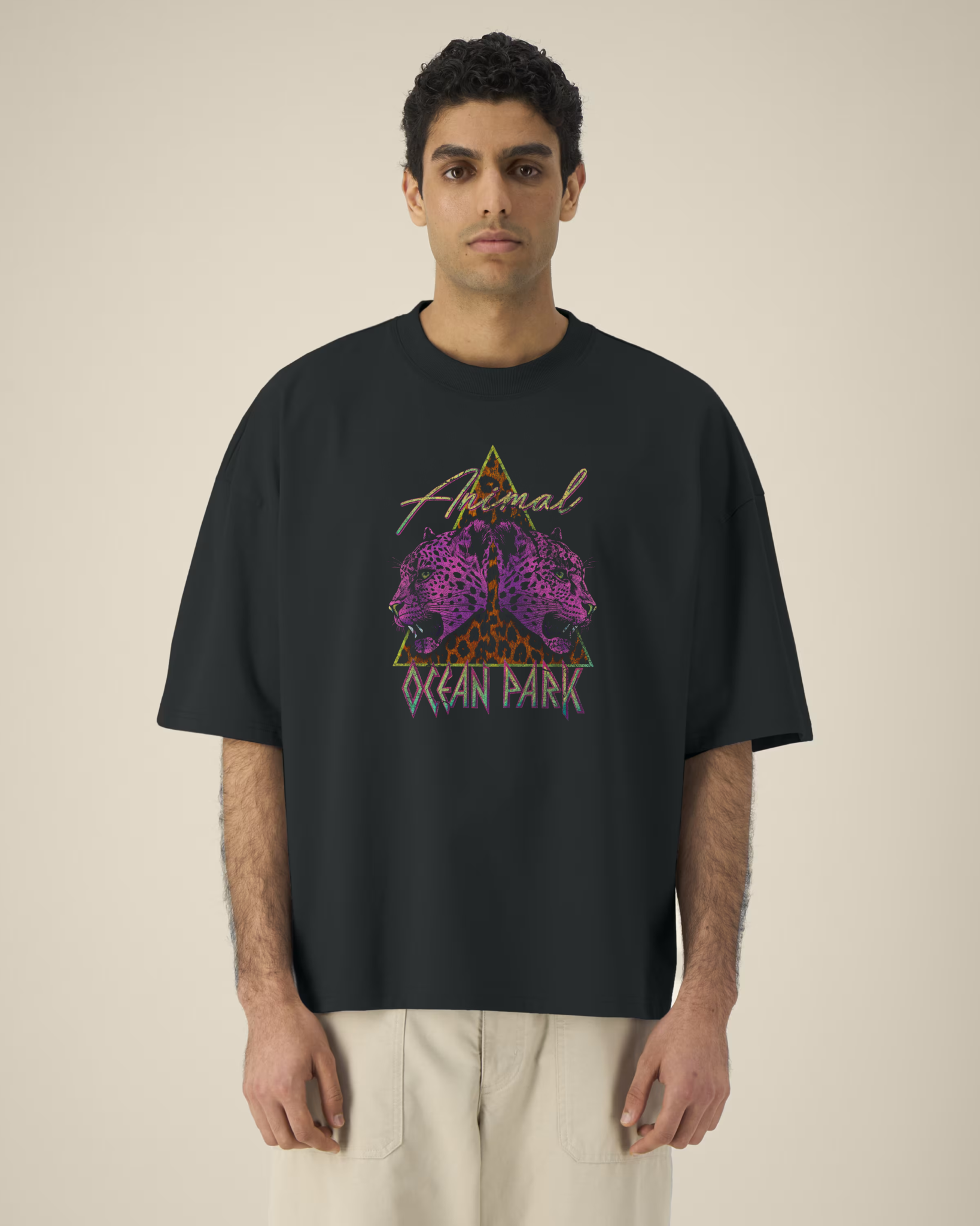 Homme portant un t-shirt noir oversize avec un graphisme central composé d'un triangle au motif léopard, de deux têtes de léopards violets de profil et des inscriptions "Animal" et "OCEAN PARK" en style néon rétro.