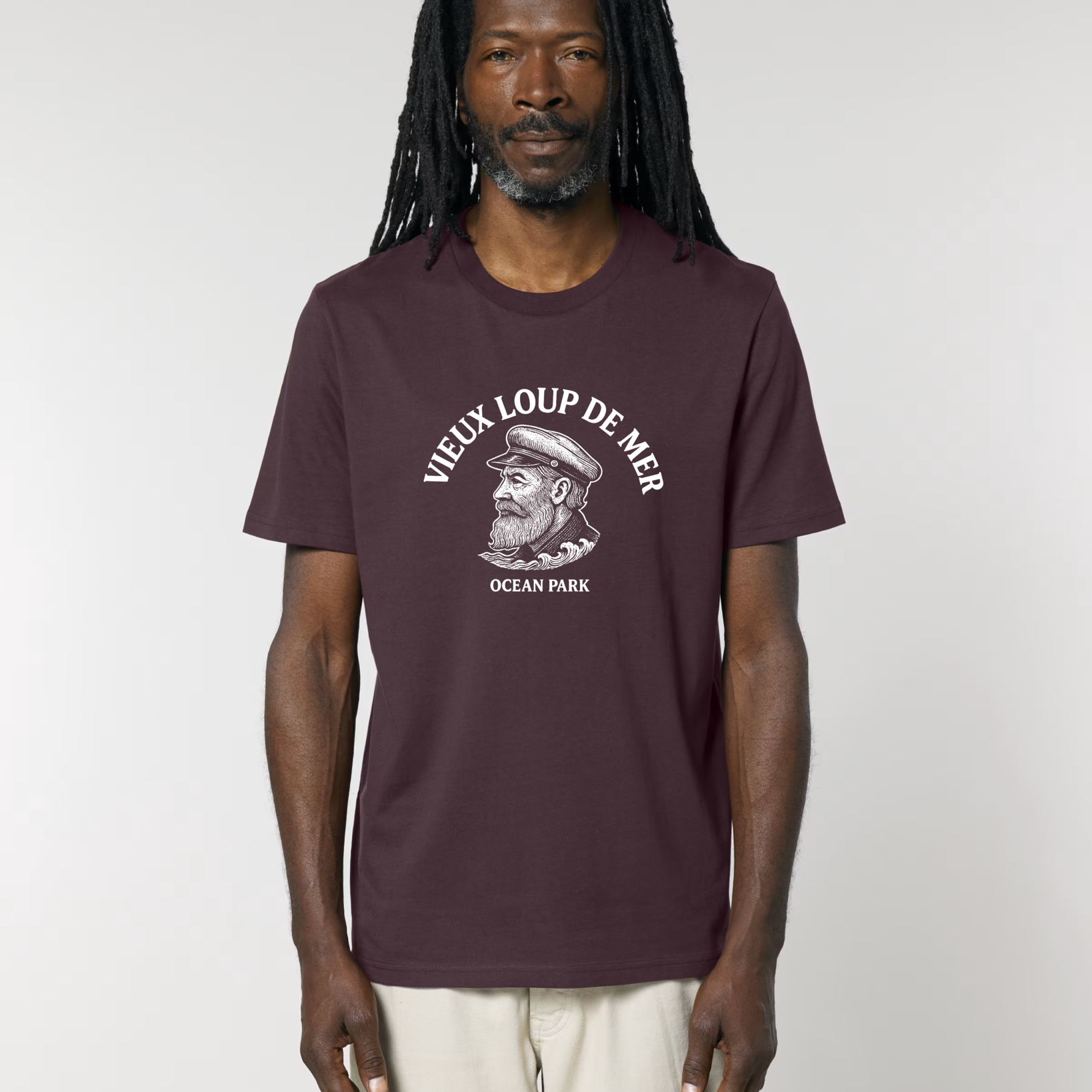 Homme portant un t-shirt de couleur bordeaux foncé (red brown) avec une illustration blanche centrale d'un vieux capitaine barbu avec une casquette de marin, surmontée du texte en arc de cercle "VIEUX LOUP DE MER".