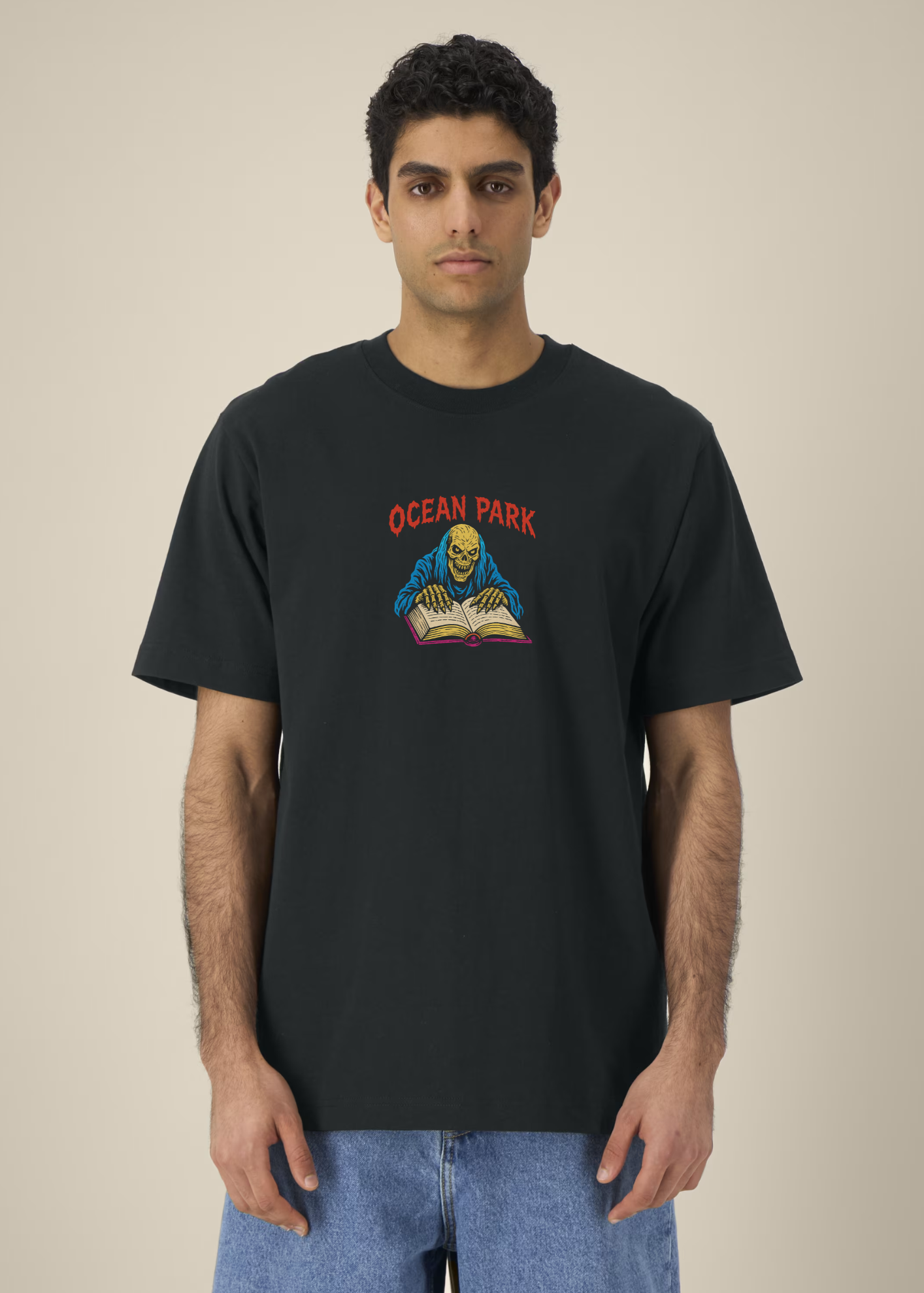 T-shirt oversize noir Ocean Park Halloween, petit print squelette et grimoire sur le devant, porté avec un jean