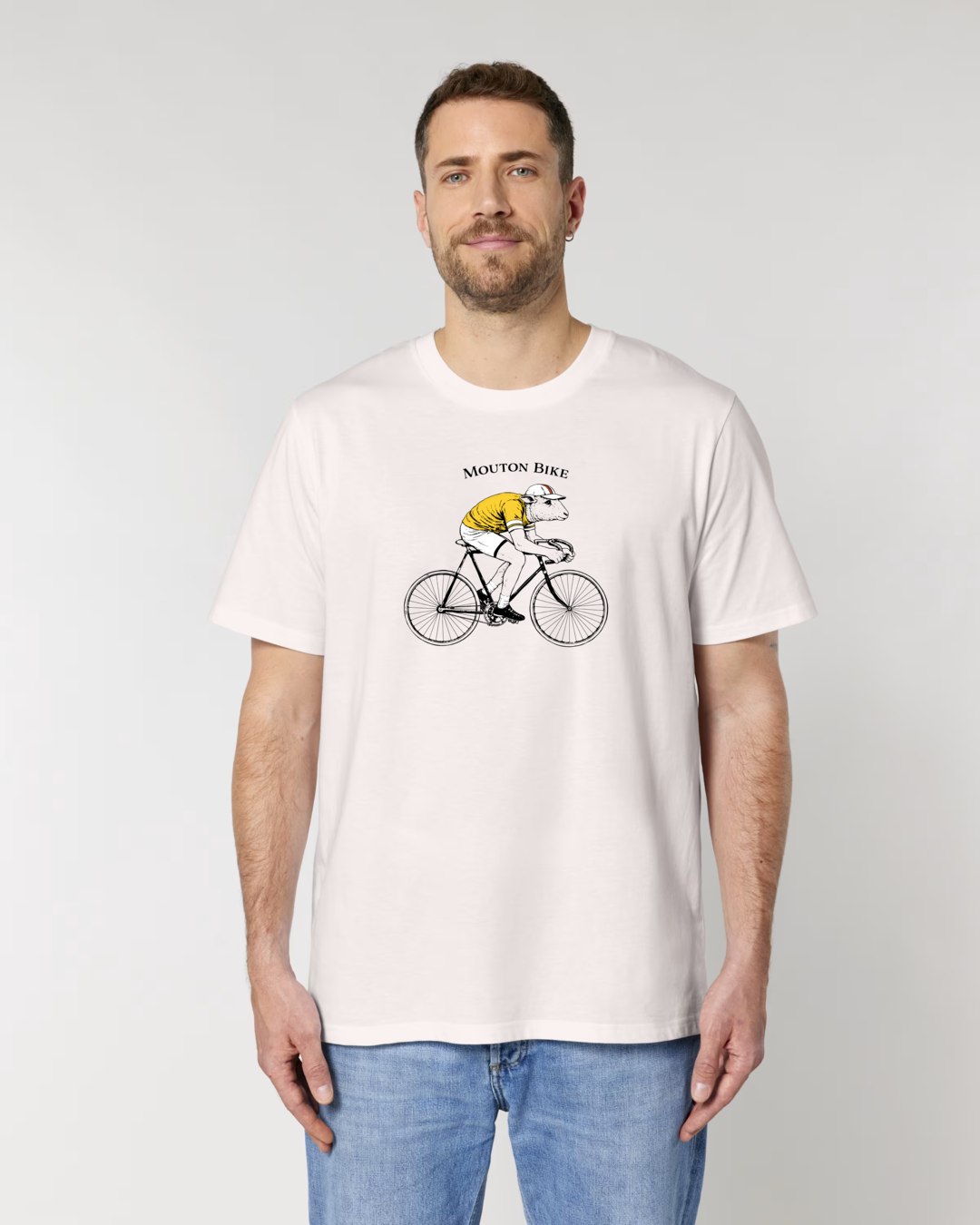 Mannequin homme portant le t-shirt en coton bio Mouton Bike d'Ocean Park, coloris Vintage White. L'illustration centrale montre un mouton cycliste avec un maillot jaune et une casquette, pédalant sur un vélo de course vintage avec l'inscription Mouton Bike.